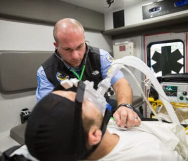 EMT assisting man in back of ambulance