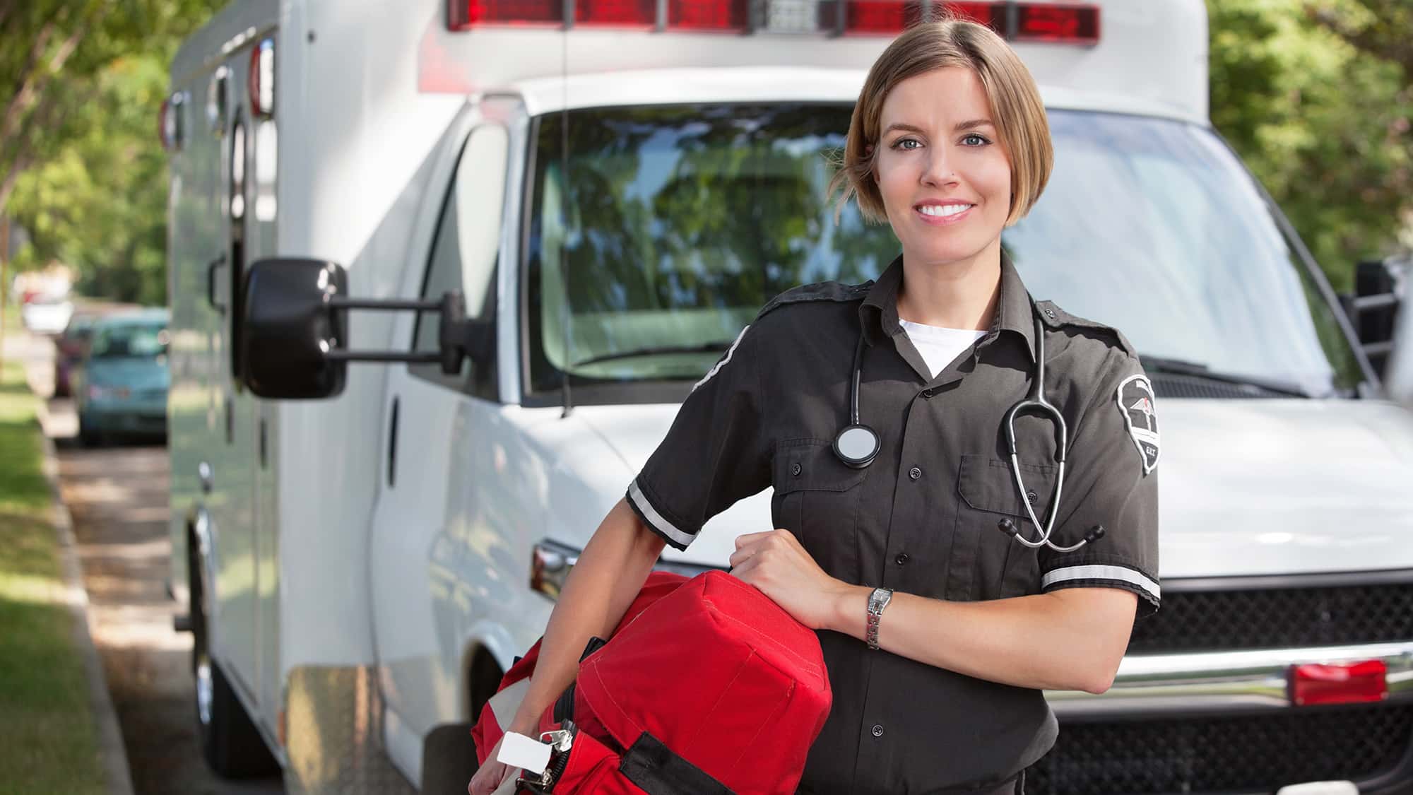 Professional Ambulance EMT standing infront of ambulance with red bag
