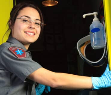 Women EMT Services | Women Smiling while getting into the back of a ambulance